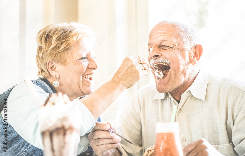 Happy retired senior couple in love enjoying bio icecream cup - Joyful elderly lifestyle concept - Wife feeding husband and having fun at bar cafe restaurant during evergreen vacation - Retro filter Happy retired senior couple in love enjoying bio icecream cup - Joyful elderly lifestyle concept - Wife feeding husband and having fun at bar cafe restaurant during evergreen vacation - Retro filter
