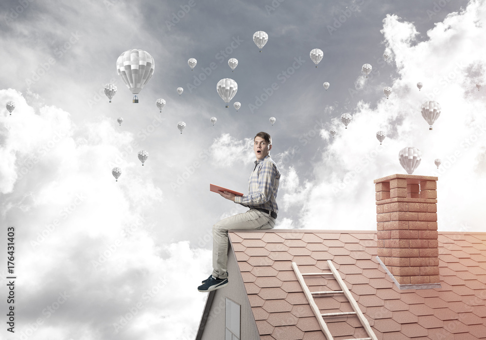 Handsome student guy reading book and aerostats flying in air Handsome student guy reading book and aerostats flying in air