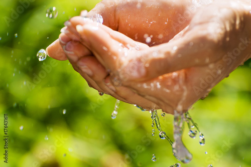 Woman washing hand outdoors. Natural drinking water in the palm. Hands with water splash, selective focus. Summer time