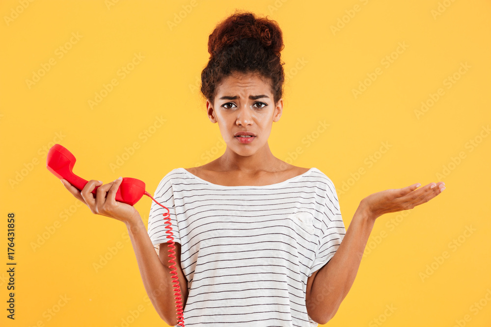 Displeased unhappy lady holding red handset while standing isolated