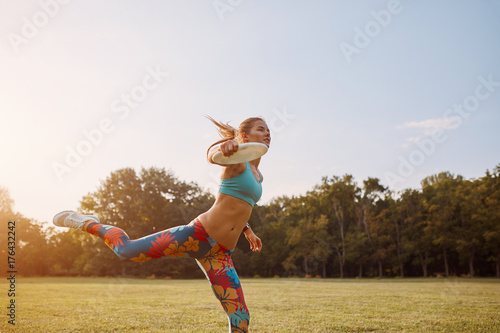 Foto Young athletic girl playing with flying disc, ultimate