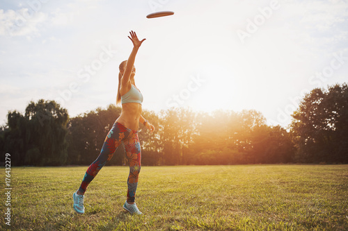 Foto Young athletic girl playing with flying disc, ultimate