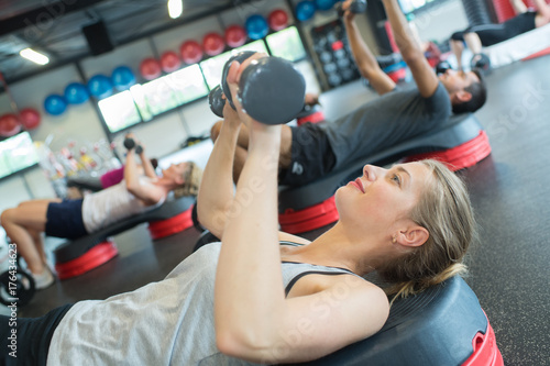 sporty female athlete lifting dumbbell in gym