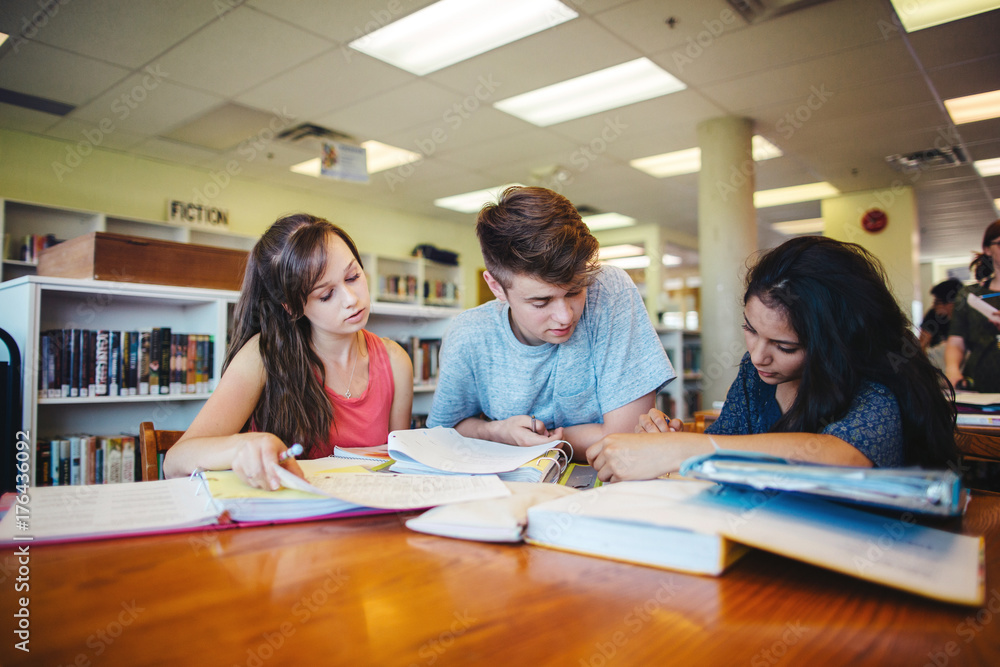 Three high school students studying together in library Three high school students studying together in library