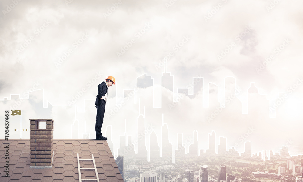 Engineer man standing on roof and looking down. Mixed media Engineer man standing on roof and looking down. Mixed media