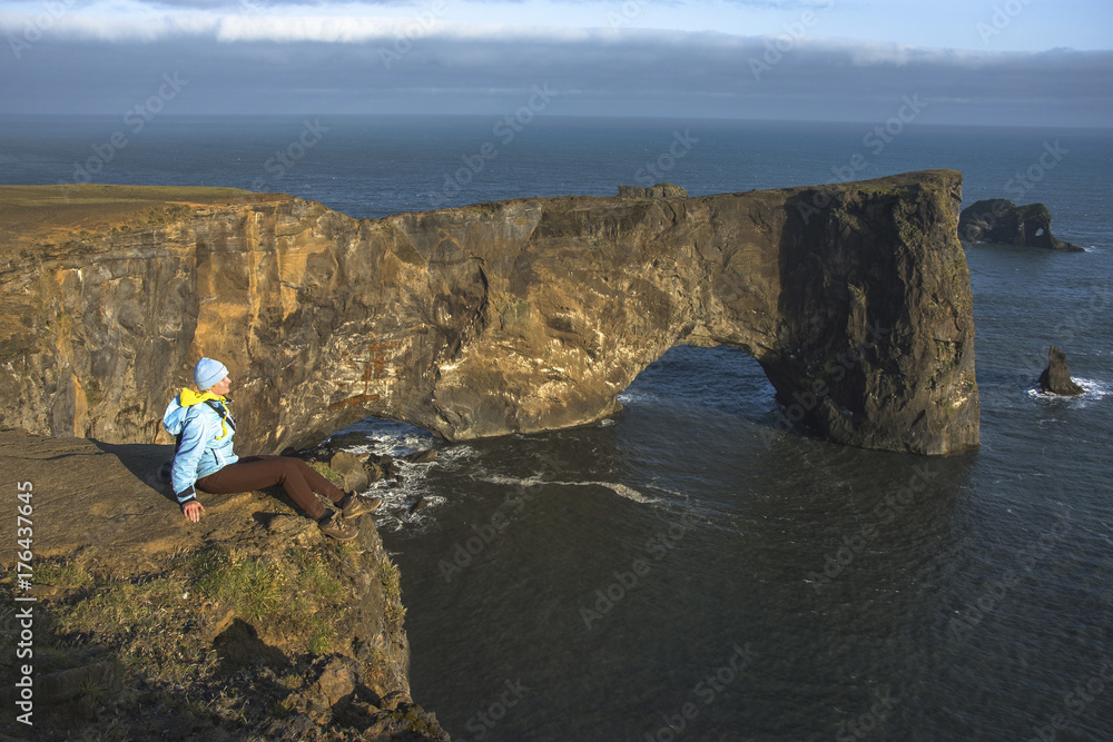 Φωτογραφία Tourist standing near natural arch of Dyrholaey Peninsula in South Iceland
