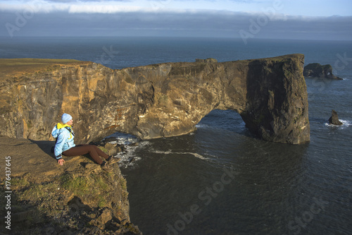 Tourist standing near natural arch of Dyrholaey Peninsula in South Iceland