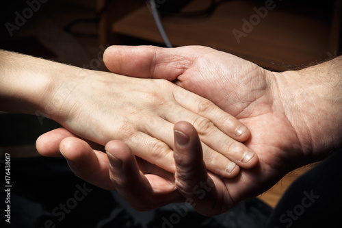 Fototapeta Naklejka Na Ścianę i Meble -  Hands of an elderly man holding the hand of a younger man.