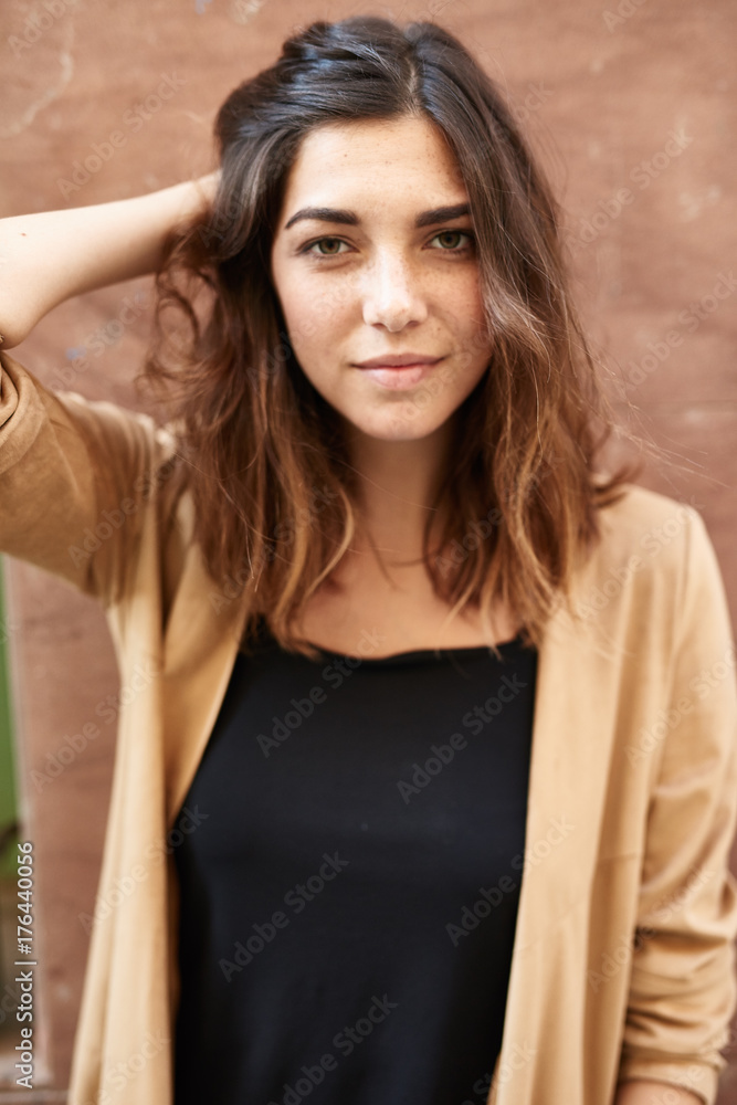 Beautiful girl in beige and black touching her hair. Beautiful girl in beige and black touching her hair.