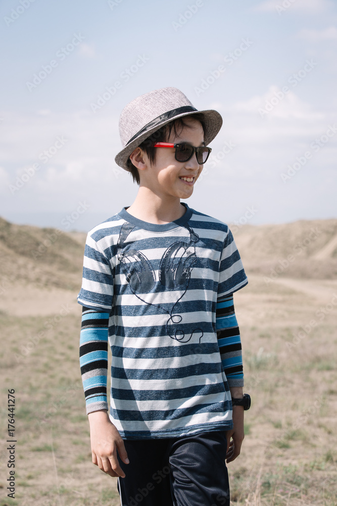 Portrait of a young boy wearing hat and sunglasses in a desert Portrait of a young boy wearing hat and sunglasses in a desert
