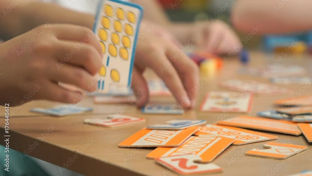 Close-up of hands of unidentified little children playing developing game in mathematics with figures, learning to count while preparing for school at desk in kindergarten Close-up of hands of unidentified little children playing developing game in mathematics with figures, learning to count while preparing for school at desk in kindergarten