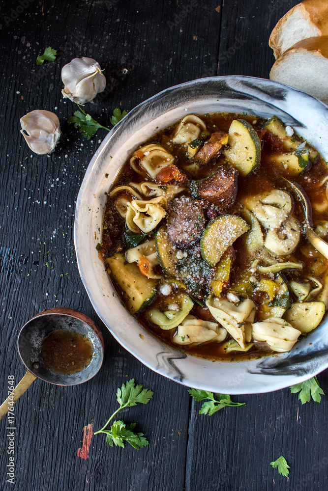 Φωτογραφία bowl of tortellini soup with sausage and zucchini top view closeup