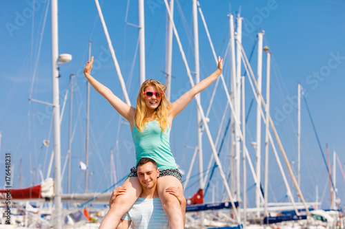 Man giving girlfriend piggyback ride on marina