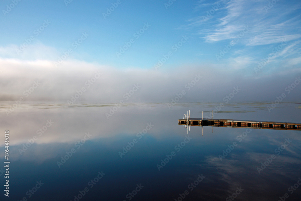 Sky and dock  reflection at lake in foggy morning