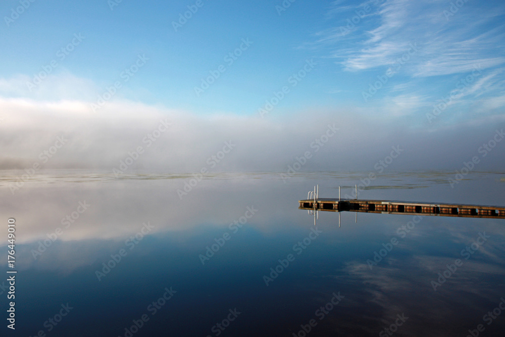 Fototapeta premium Sky and dock reflection at lake in foggy morning