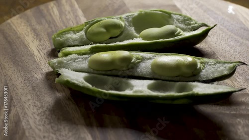 Rotating shot of two fava bean pods opened up with the green beans inside. photo