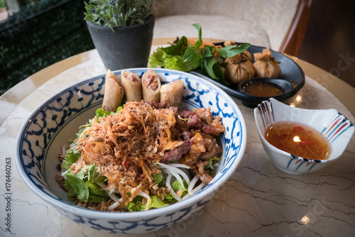 Vietname food in the restaurant in the evening.There are noodles, fried meat and vegetable. photo