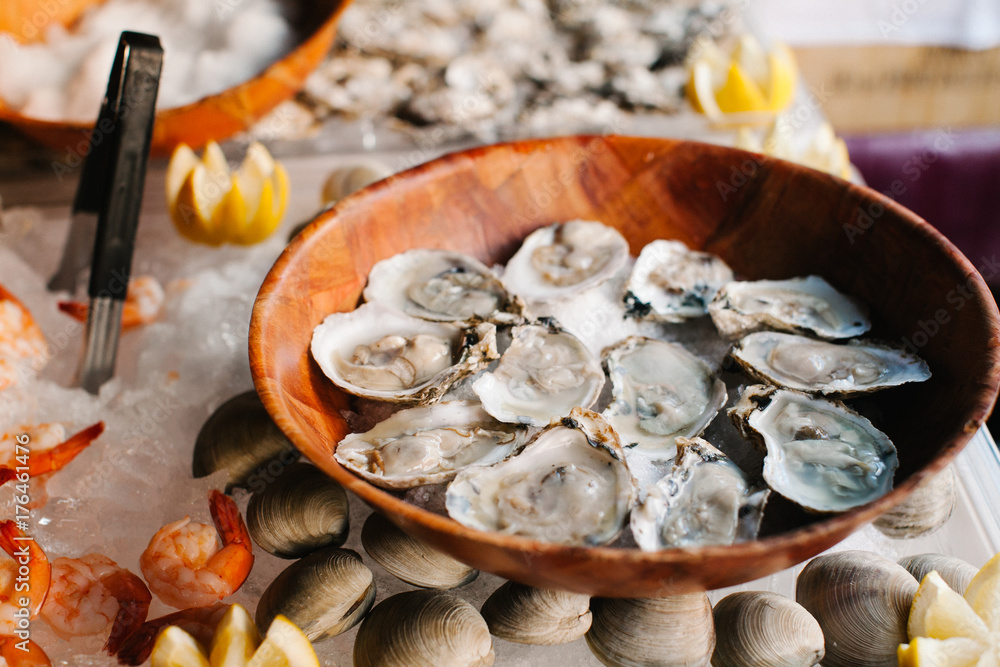 A dozen of raw oysters on a wooden plate