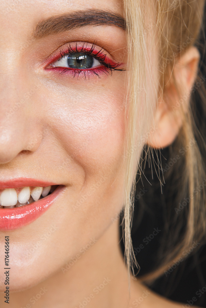 Close up on half face of a gorgeous smile of a beautiful happy blonde woman. Her lips are painted with bright red lipstick, skin is soft and natural and do not miss her stunning white teeth. Close up on half face of a gorgeous smile of a beautiful happy blonde woman. Her lips are painted with bright red lipstick, skin is soft and natural and do not miss her stunning white teeth.