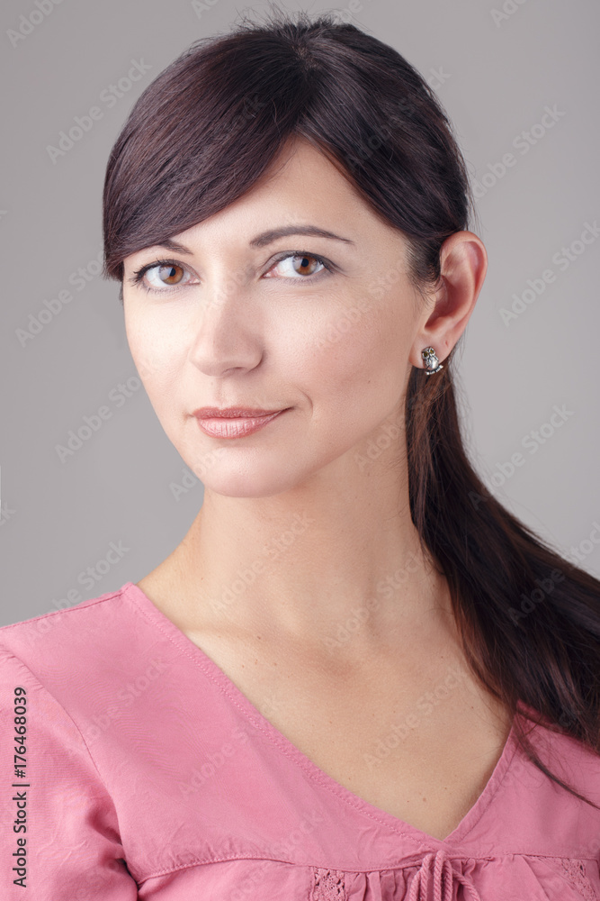 Closeup portrait of beautiful smiling young brunette Caucasian woman with brown eyes looking in camera. Girl female with long dark hair in pink dress. Studio beauty shot. Closeup portrait of beautiful smiling young brunette Caucasian woman with brown eyes looking in camera. Girl female with long dark hair in pink dress. Studio beauty shot.