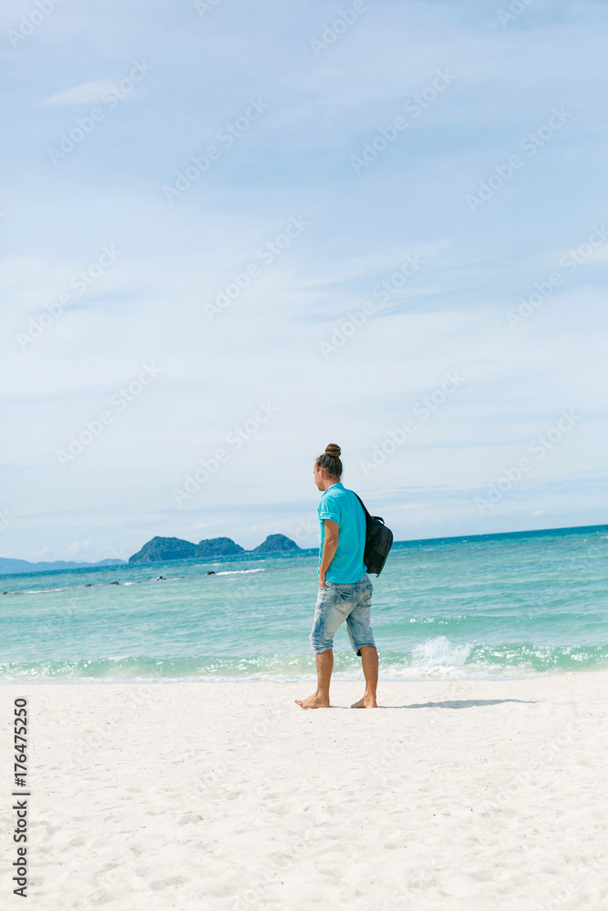 hadsome man tourist walking on the beach