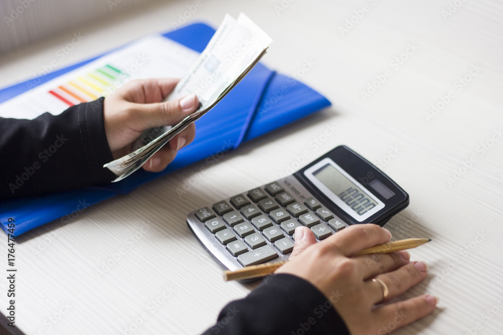 woman counts the money in the office. business graphics calculator and a pen. woman counts the money in the office. business graphics calculator and a pen.