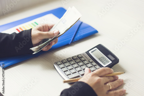 woman counts the money in the office. business graphics calculator and a pen.