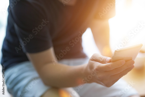 Closeup of young man using smartphone with sun flare .