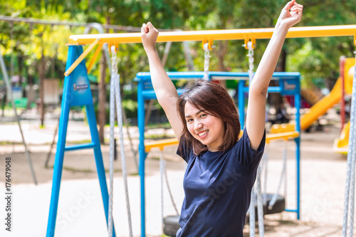 teen rise up two hand to show her strong healthy women and smile in the park