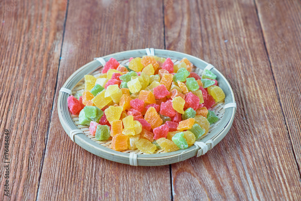 Delicious sweet candied fruit on a plate on a wooden background. Delicious sweet candied fruit on a plate on a wooden background.
