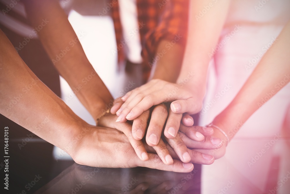 Business people stacking hands on table in office Business people stacking hands on table in office