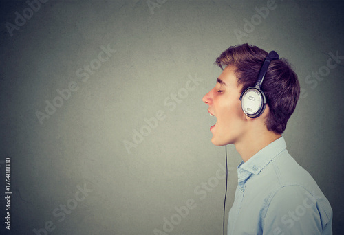 Handsome guy with headphones in blue shirt listening to music and singing