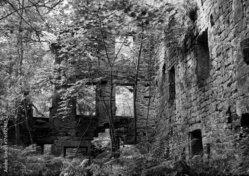 monochrome image of the derelict staups mill a large ruin in woodland in calderdale west yorkshire photo