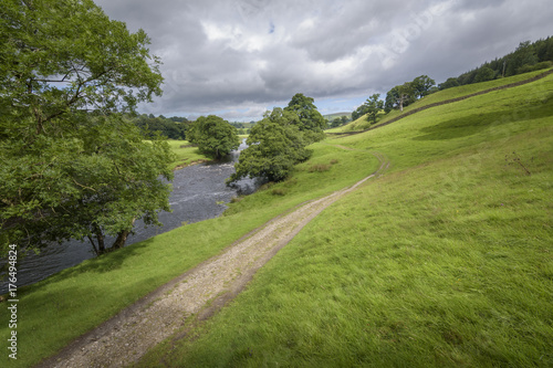 Characteristic English Landscape green field and the river Wharfe with path leading into the countryside