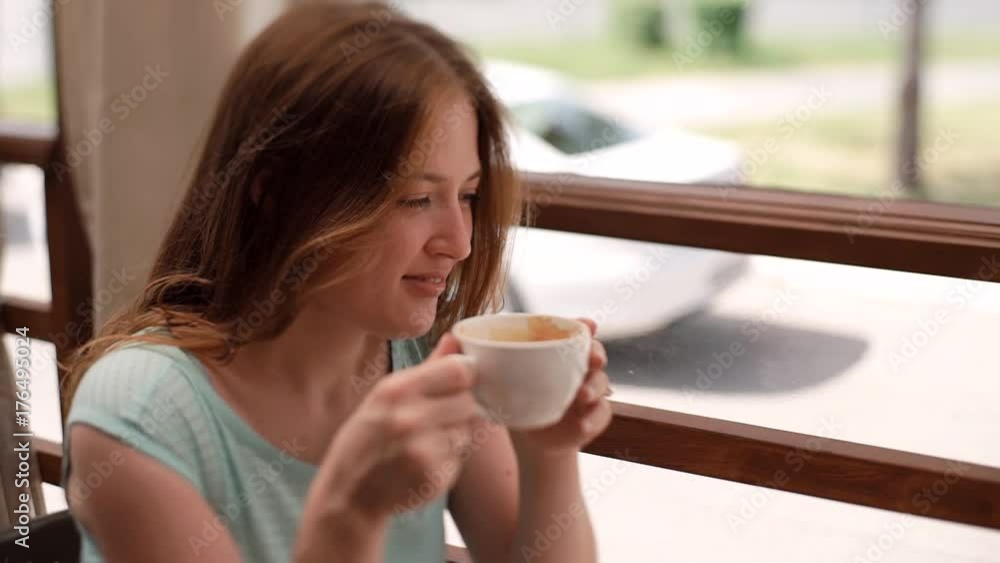 the girl in a blue dress is drinking coffee in a cafe. the girl in a blue dress is drinking coffee in a cafe.