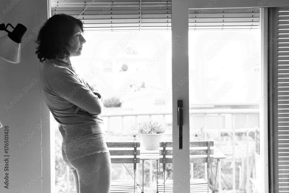 middle aged woman looking out the window at home middle aged woman looking out the window at home