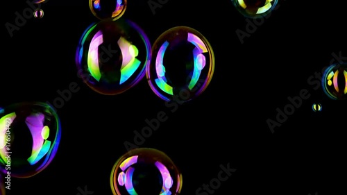 Colorful soap bubbles fly across black background. 