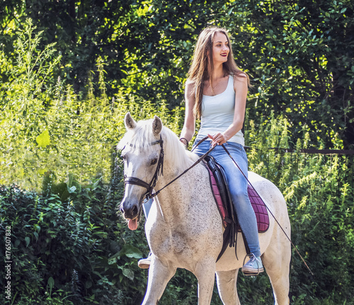 A beautiful girl is riding a white horse. Sincere emotions.