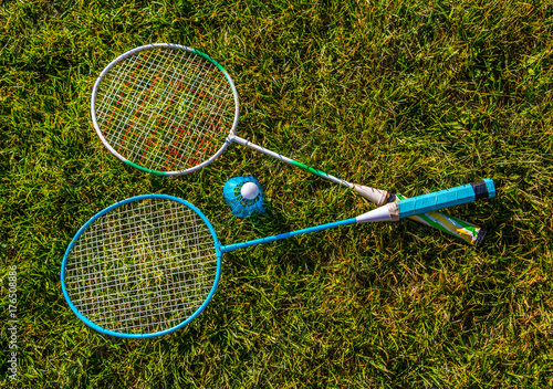 Shuttlecock and badminton rackets outdoor on green grass