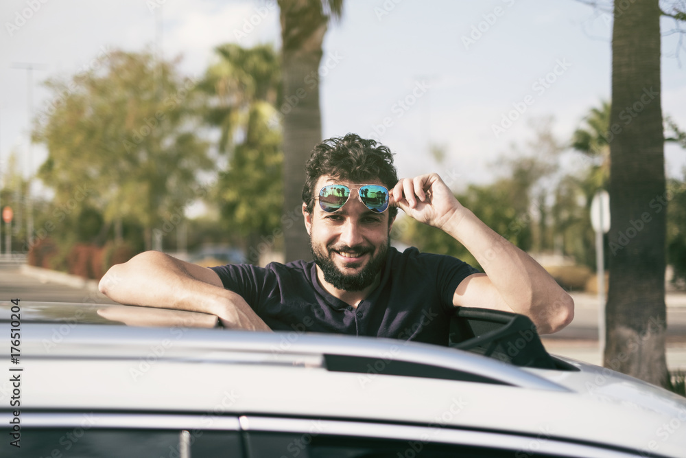 Bearded man driving car and smile looking at camera with sunglasses