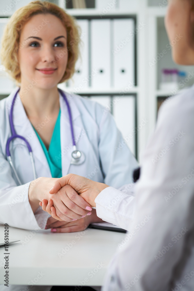 Doctor and patient shaking hands, close-up. Physician talking about medical examination results. Medicine, healthcare and trust concept Doctor and patient shaking hands, close-up. Physician talking about medical examination results. Medicine, healthcare and trust concept