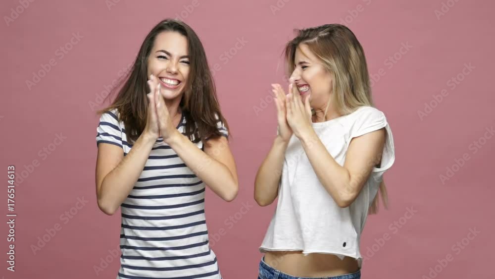 Happy caucasian friends ladies clapping and jumping over pink Happy caucasian friends ladies clapping and jumping over pink