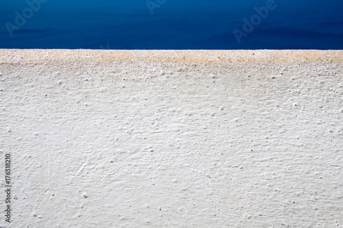 white painted wall detail on the background of deep blue sea, Santorini Greece.
