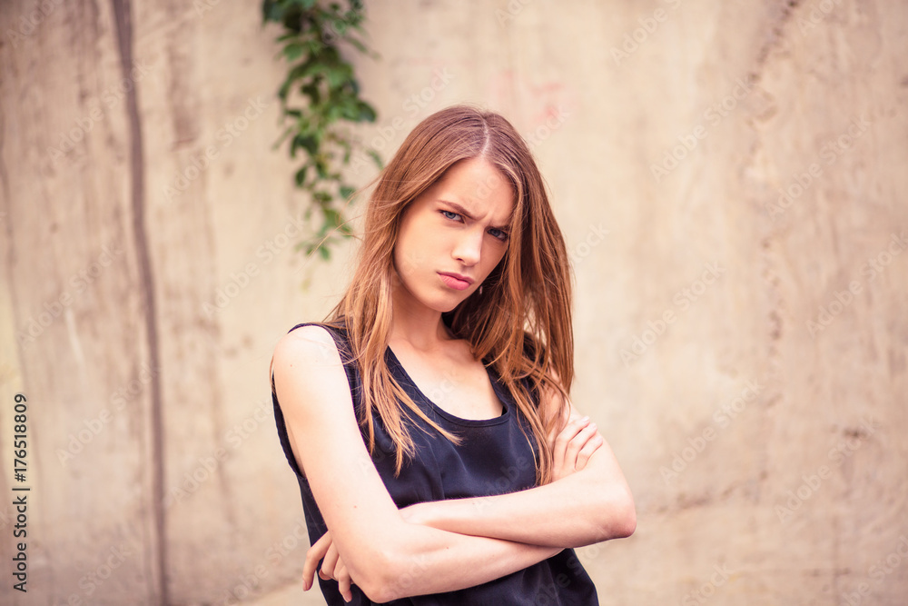 Unsatisfied face of young beautiful woman. Pretty girl standing outdoors showing different emotions. Toned image.