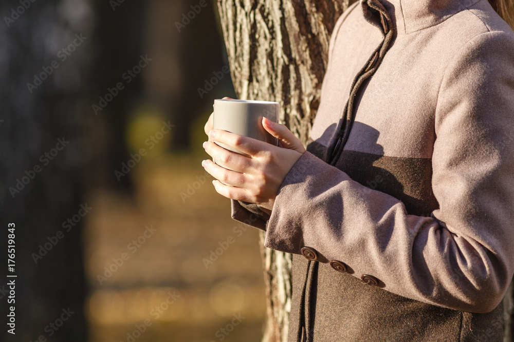 holding coffee or tea from cup in autumn park holding coffee or tea from cup in autumn park