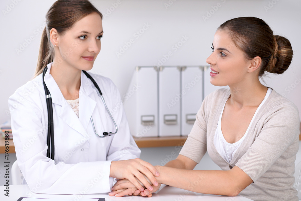 Doctor reassuring her female patient while sitting at the desk. Medicine, help and health care concept Doctor reassuring her female patient while sitting at the desk. Medicine, help and health care concept
