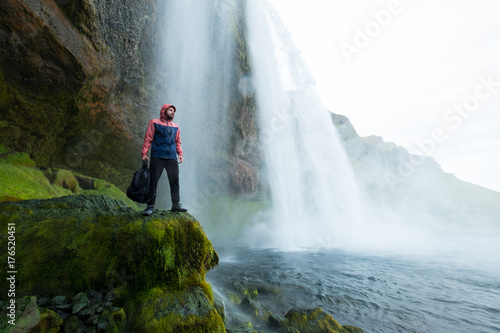 Adventure man by skogafoss waterfall, nature on Iceland. Young man visiting nature landscape.