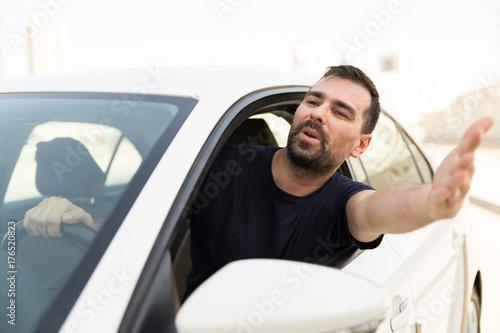 Angry driver pissed off by drivers in front of him and gesturing with hands. Road rage traffic jam concept.