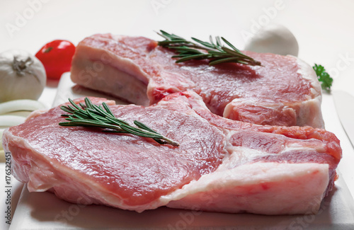 Raw ribeye pork steaks on white painted cutting board