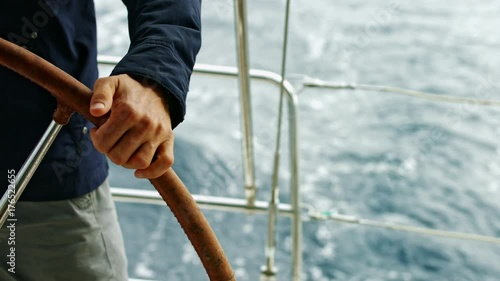 Man holding steering wheel. Controlling a yacht